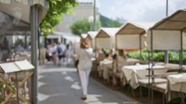İtalya 'nın başkenti Capri' de lüks bir caddede, bokeh ışıklı gölgeliklerin altında gezinen turistler, rahat bir yaz günü atmosferini yakalıyorlar..