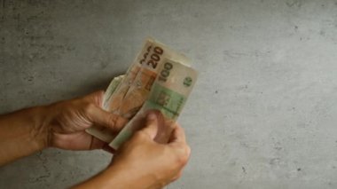 Gri beton arka planda, mali işlemleri ve para işleme örneklerini gösteren Czech Koruna banknotlarını tutan eller