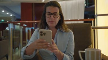 Evin içinde akıllı telefon kullanan bir kadın modern yaşam tarzı teknolojisi ve rahatlama öneriyor.