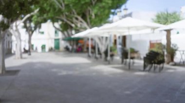 Lanzarote, kanarya adaları, bulanık arka planda ağaçlar, beyaz şemsiyeler ve güneşli bir avluda oturan insanlar..