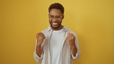 Yakışıklı genç adam, izole edilmiş sarı arka plana karşı kutlama yapıyor.