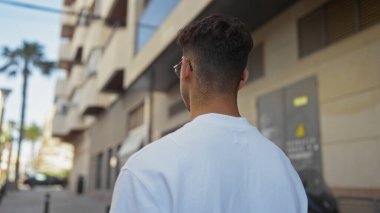 Arka planda şehir binaları olan, şehir merkezindeki Latin kökenli genç adam..