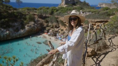 İspanyol kadın Mallorca, İspanya 'da güneşli bir günde doğa ve berrak turkuaz sularla çevrili manzaranın tadını çıkarıyor.