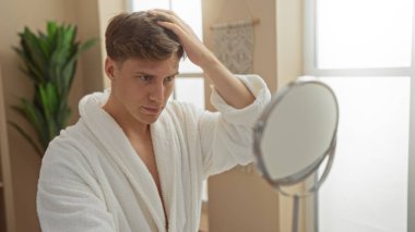 Kaplıca cüppeli genç adam içerideki bir sağlık merkezindeki aynada saçlarını kontrol ediyor.