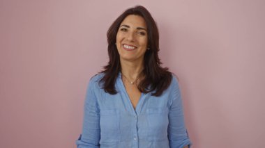 Pembe duvara gülümseyen bir kadın, orta yaşlı, mavi bluz giyen, soyutlanmış, olgun, İspanyol, kadın, mutlu, güzel