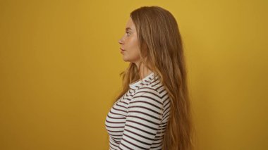 Sarı arka planda izole edilmiş çizgili tişört giyen genç sarışın kadın profil görünümünde