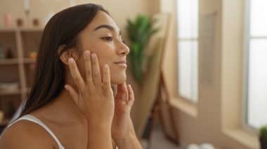 Güzellik merkezindeki çekici esmer kadın tenini inceliyor nazikçe yüzüne dokunuyor.