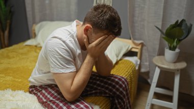 Genç bir İspanyol adam evdeki yatak odasında bir yatakta oturuyor, elleriyle yüzünü örtüyor, rahat ve kapalı bir ortamda bir stres anı veya tefekkür ediyor..
