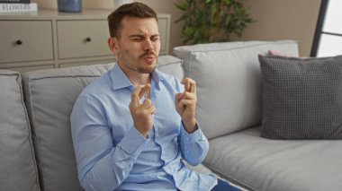Sakallı yakışıklı genç bir adam oturma odasında oturuyor, parmaklarını çapraz yapıyor ve bir dilek diliyor..