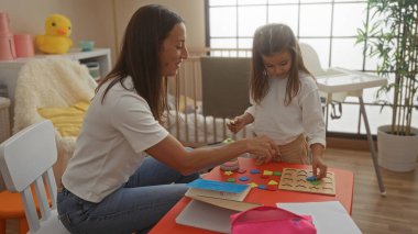 Evde kızına evde öğretmenlik yapan bir kadın yatak odasında sevgi ve bağlılık gösteriyor. Eğitici oyuncaklarla, parlak ve besleyici bir ortamda..