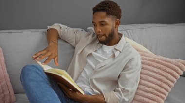 Genç adam oturma odasında kitap okuyor..
