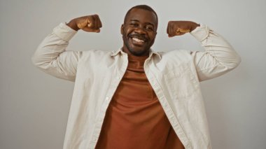 Genç Afrikalı adam izole edilmiş beyaz arka plan üzerinde kaslarını esnetiyor. Güç ve kendine güven gösteriyor.