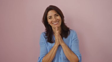 Pembe arka planda gülümseyen mavi gömlekli kadın mutlu ve mutlu görünüyor. Minnettarlık ve pozitifliği işaret ediyor.