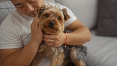 Genç bir Asyalı evcil köpeğini oturma odasında tutarak Çin 'de sıcak, kapalı bir ev ortamını gösteriyor..