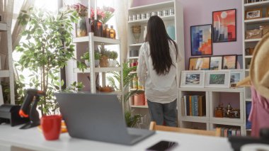 Güzel dekore edilmiş bir ev dekorasyonunda etrafı bitkilerle, sanatla ve raflardaki renkli eşyalarla çevrili bir kadın Çin 'de rahat bir iç mekan ortamı yaratıyor..