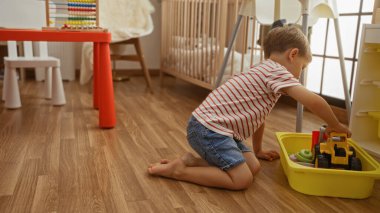 Küçük çocuk anaokulunun zemininde oyuncaklarla oynuyor, ev ortamında mutlu bir çocukluk yaşıyor..