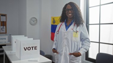 A beautiful african american woman in a lab coat stands smiling in an electoral college room with venezuelan flags and voting booths. clipart