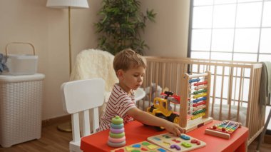 Küçük çocuk evde eğitici oyuncaklarla oynuyor rahat bir ev ortamında.