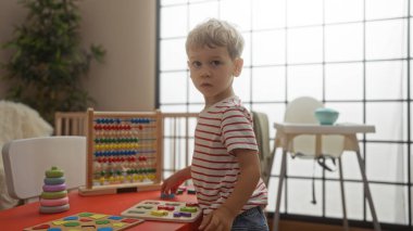 Anaokulunda eğitici oyuncaklarla oynayan küçük bir çocuk, parlak, neşeli iç mekanda renkli nesnelerle çevrili..