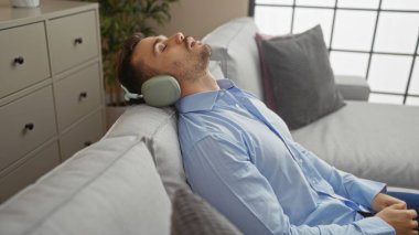 Yakışıklı, sakallı, rahat bir apartman dairesinde kulaklıkla rahatlayan bir İspanyol..