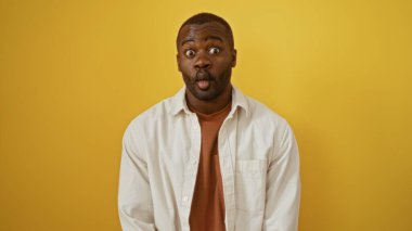 Yakışıklı Afro-Amerikalı adam izole edilmiş sarı arka planda komik bir surat yapıyor.