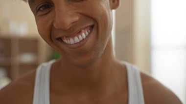 Handsome young hispanic man smiling in an indoor wellness spa room showcasing relaxation and self-care in a serene environment clipart