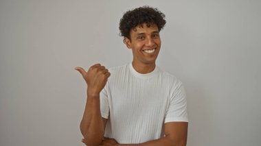 Genç İspanyol adam, izole edilmiş beyaz arka plan üzerinde başparmağıyla iki tarafı işaret ediyor.