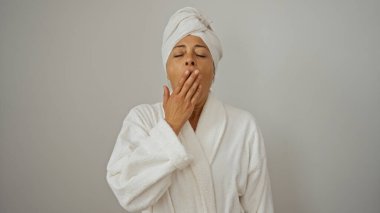 Bornoz ve havluyla esneyen bir kadın izole edilmiş beyaz arka planda