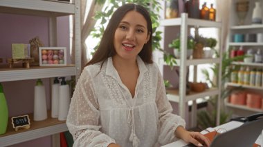 Güzel dekore edilmiş bir ev dekorasyonunda gülümseyen esmer bir kadın. Arka planda çeşitli çekici iç dekorasyonlar var.