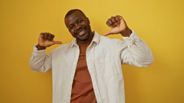 İzole edilmiş sarı bir arka planda kendini gösterip gülümseyen genç adam.