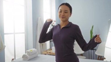 Huzurlu bir kaplıca ortamında mutlu bir şekilde dans eden kadın, modern bir salonda parlak ışıklandırma ve zarif bir dekorla rahatlık ve rahatlık sergiliyor..