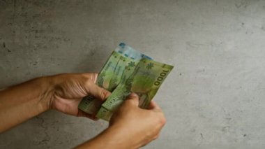 Şili pezolarının beton duvar arkaplanını sayan eller, Şili para biriminin çeşitli değerlerini gündelik bir ortamda gösterir