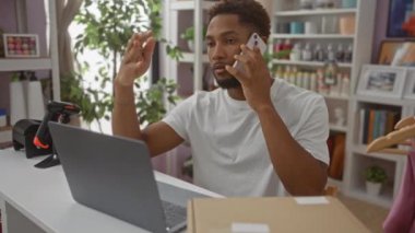 Ev dekorasyonu mağazasında çalışırken cep telefonuyla konuşan genç bir adam. Etrafı çeşitli dekorasyonlar ve ev bitkileriyle çevrili.