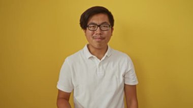 İzole edilmiş sarı arka planda genç bir adam olumlu bir jestte başparmak gösteriyor.