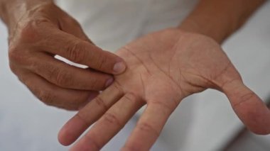 Genç İspanyol adam, tedavi seansı sırasında elleri ve avuç içlerine odaklanmış bir sağlık merkezindeki güzellik salonunda el muamelesi görüyor.