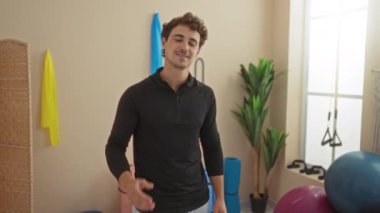 Spor salonundaki genç adam, modern bir spor merkezinde kendine güvenerek kollarını kavuşturur..