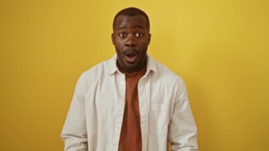 Gömlekli Afro-Amerikan bir adam şaşırdı. İzole edilmiş sarı arka planda parmak göstererek komik bir tepki yakaladı.