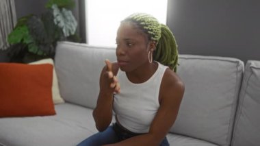 Evde örgü ören bir kadın oturma odasında kanepede otururken burnunu çimdikliyor ve modern apartman dekorundaki nahoş kokuya tepki veriyor..