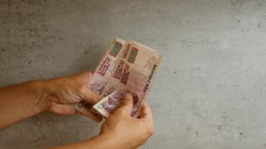 Elleri Mısır banknotlarını beton bir arka planda tutan, on sterlinlik banknotlar da dahil olmak üzere Mısır 'dan gelen paraları gösteren eller