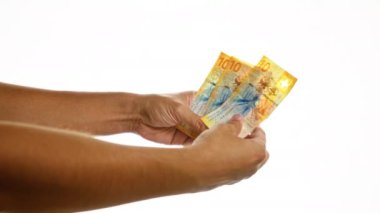 Beyaz bir arkaplan üzerinde izole edilmiş İsviçre frangı tutan eller keskin odak ve canlı renklerde birden fazla on franklık banknotlar sergiliyor..