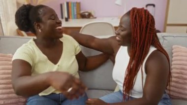 Yumuşak pembe dekorlu ve modern bir iç mekanı olan oturma odasında sevgi ve sevgiyi yansıtan rahat bir kanepeye sarılan kadınlar.