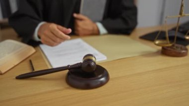 Yargıç tokmağı elinde tutarken ofis ortamında kitap ve adalet terazilerini ahşap bir masada okurken.