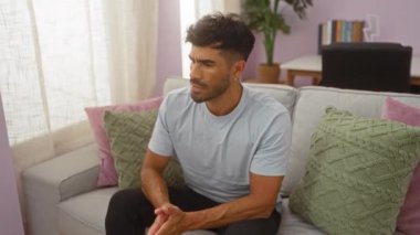 Modern bir iç mekanda rahat yastıkları olan bir oturma odasında rahat bir koltukta oturan genç adam hayal kırıklığı yaşıyor.