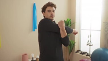Genç İspanyol bir adam spor salonunda spor aletleri ve doğal ışıklandırma ile esneme sportif yaşam tarzı ve yakışıklı karizmatik tavırlarıyla