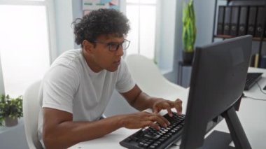 Modern ofis ortamında bilgisayarın başında sırt ağrısı çeken genç bir adam masa başındaki zavallı ergonominin rahatsızlığını vurguluyor..