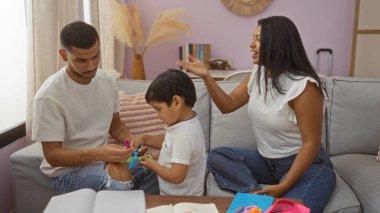 Latin ailesi, bir erkek, kadın ve çocukla birlikte sıcak bir oturma odasında vakit geçiriyor..