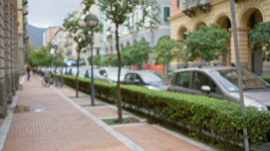 La Spezia, İtalya 'da bir caddenin bulanık görüntüsü, odağını kaybetmiş ağaçlar, park edilmiş arabalar ve binalar yürüyüş yolu boyunca bir bokeh etkisi yaratıyor..