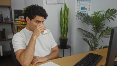 Yakışıklı, İspanyol asıllı bir adam. Kapalı bir ofiste masa başında çalışırken kahve içiyor. Duvarında bitki ve çizelgeler var..