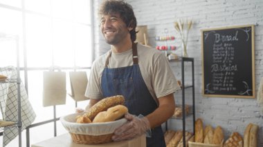 Fırında elinde bir sepet ekmek tutarken gülümseyen genç bir adam..