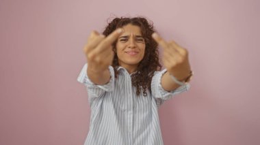 Hispanik kadın iki eliyle pembe izole bir arka plana karşı kaba bir hareket gösteriyor. Öfke ve hayal kırıklığını ifade ediyor.